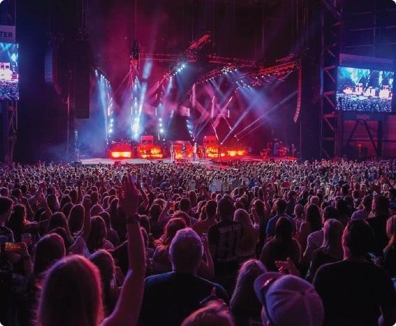 a large crowd of people in front of a stage with a large screen