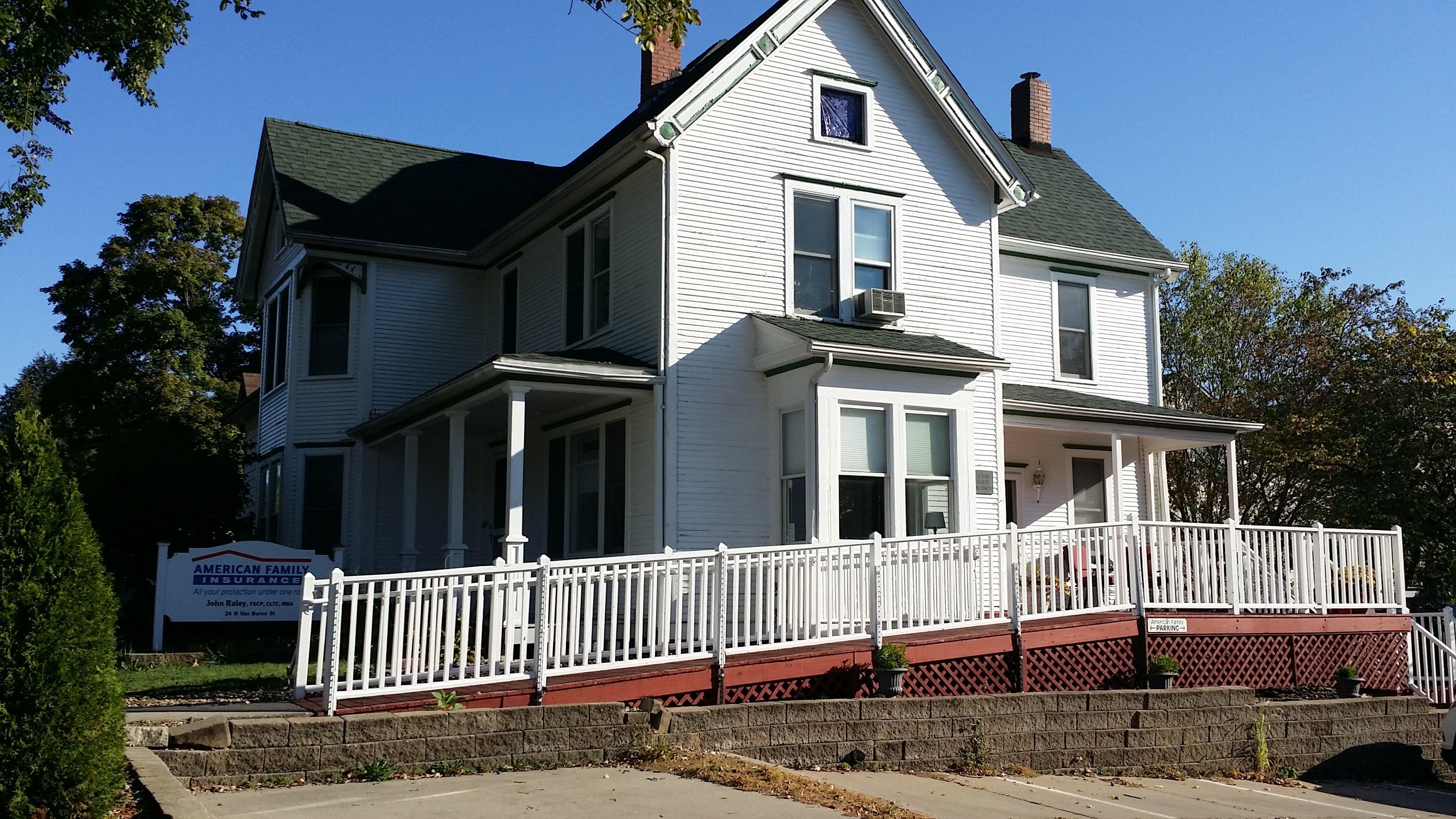 a white house with a red railing with Ronald Reagan Boyhood Home in the background