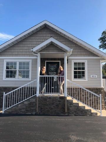 a couple of women standing on the porch of a house