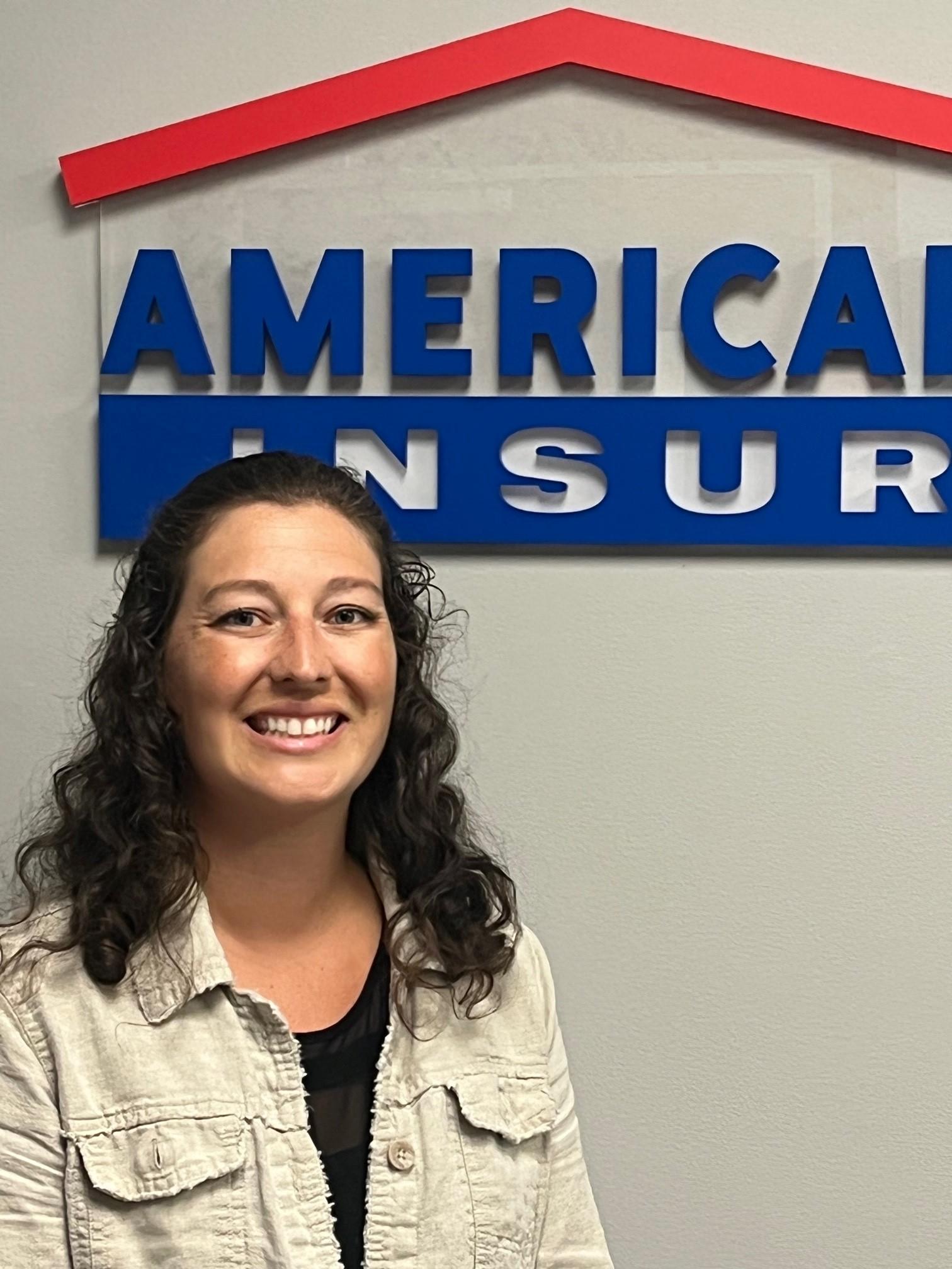 a woman smiling in front of a sign