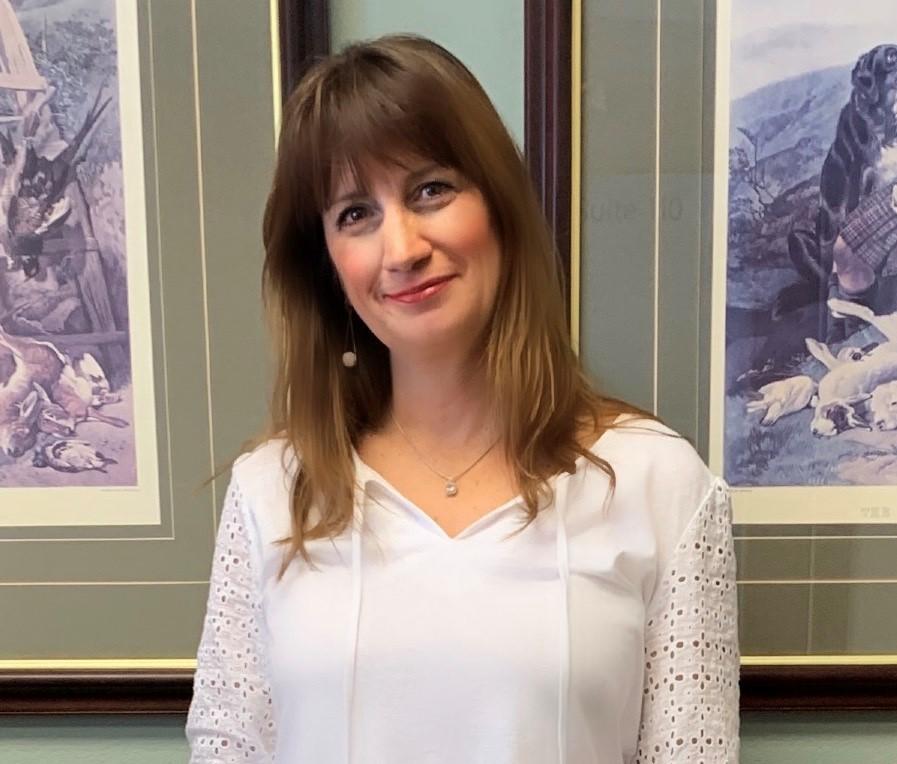 a woman smiling in front of a wall of paintings