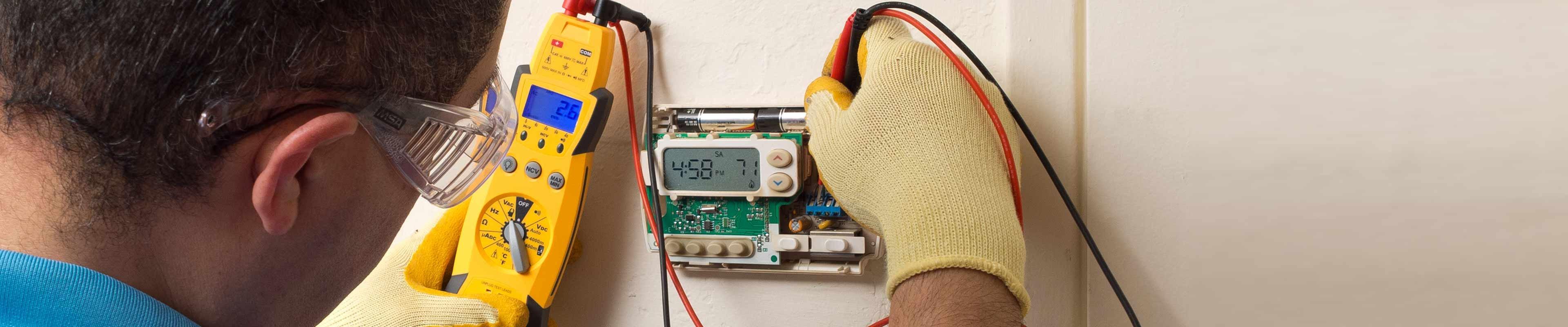 Image of a furnace serviceman working on a thermostat.