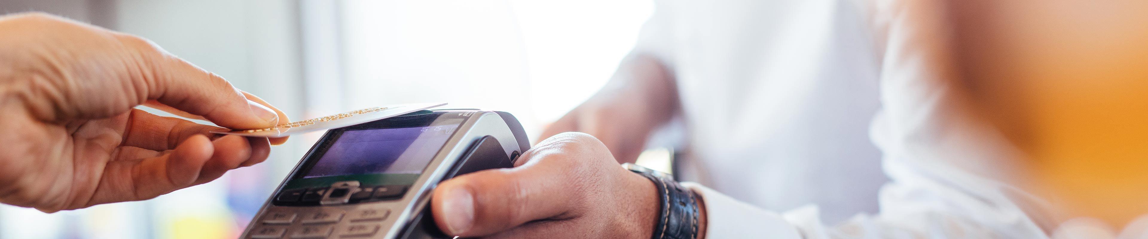 Man swiping credit card on device to make a purchase