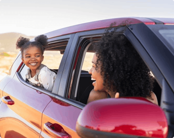 Happy mother looking at daughter through window while someone else drives.