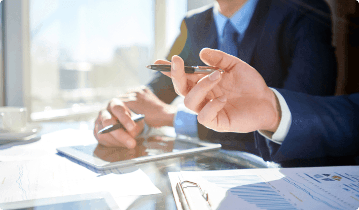 A close-up of two businesspeople gesturing at a desk.   