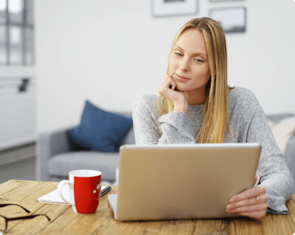 A person sitting in front of their laptop, reading its screen.