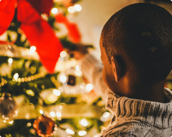 A small child admiring a Christmas tree. 