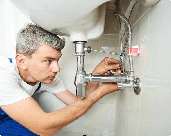 Image of a homeowner making repairs to plumbing under the sink.