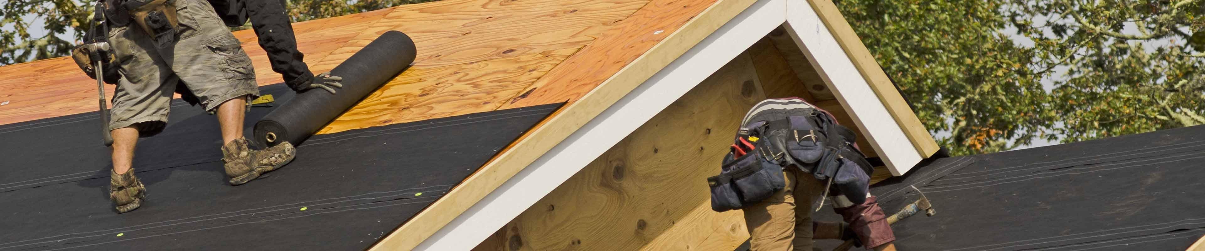 Workers laying a roof seal on a house