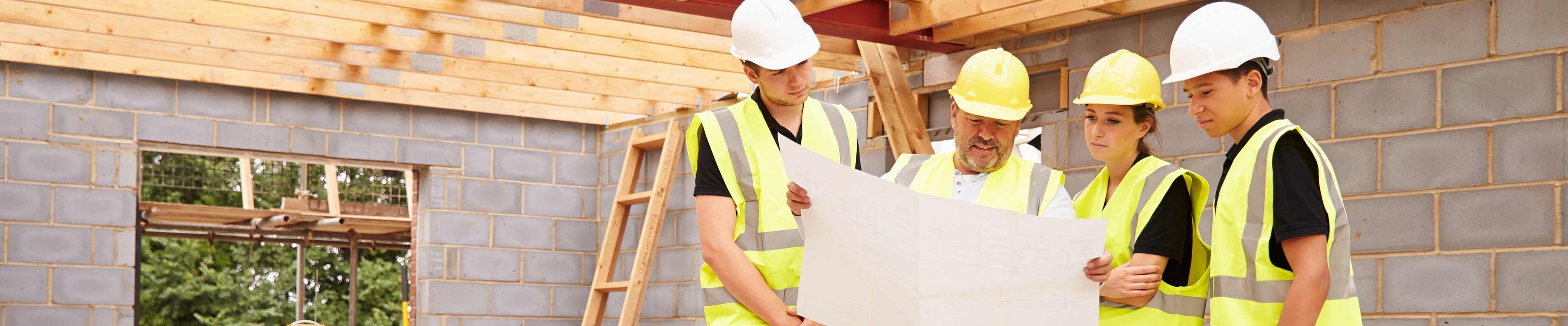 Construction workers looking at blueprint on site.