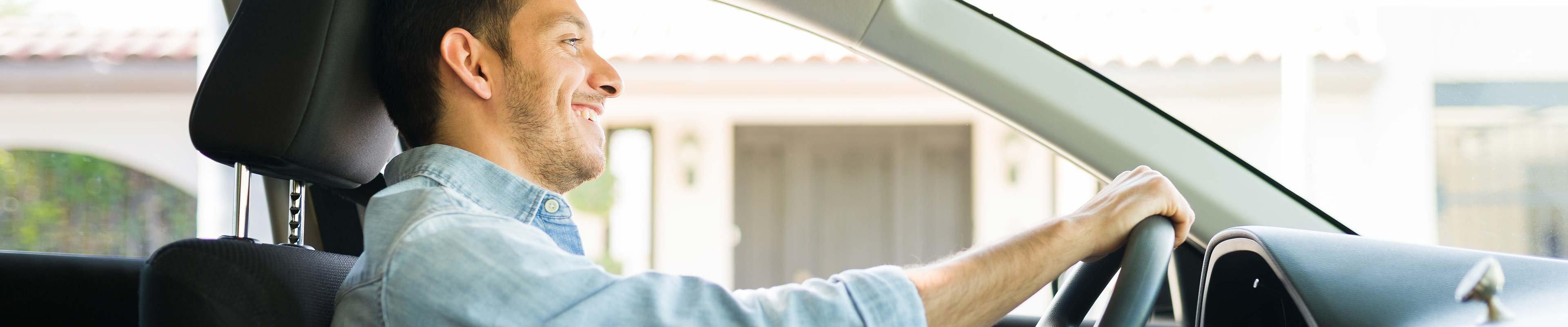 Happy young man buckled up in driving seat web