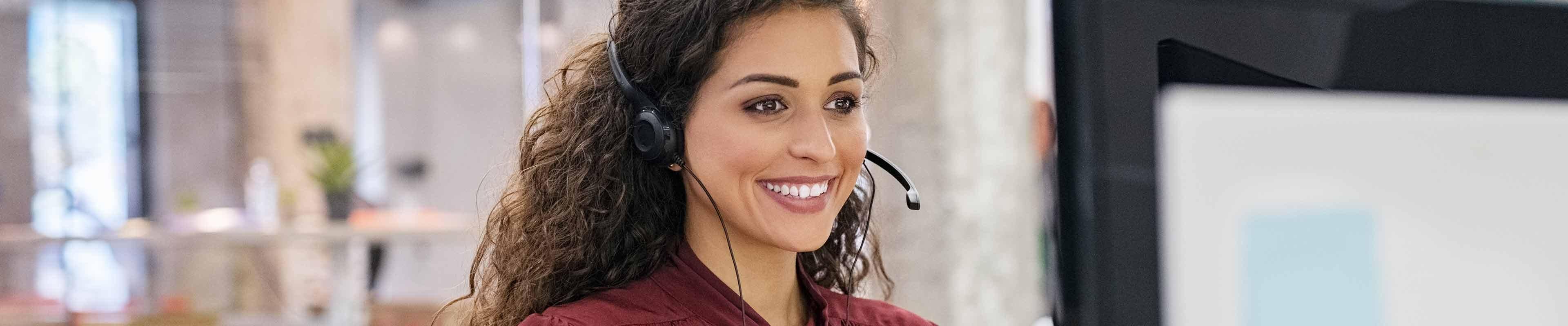 Young woman sitting in front of a computer with a headset on