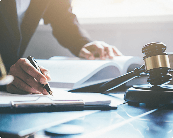 A black female lawyer signing documents on a desk with a gavel and scales of justice. Renters liability insurance can help if the unexpected happens and you're found responsible for property damage or bodily injury.