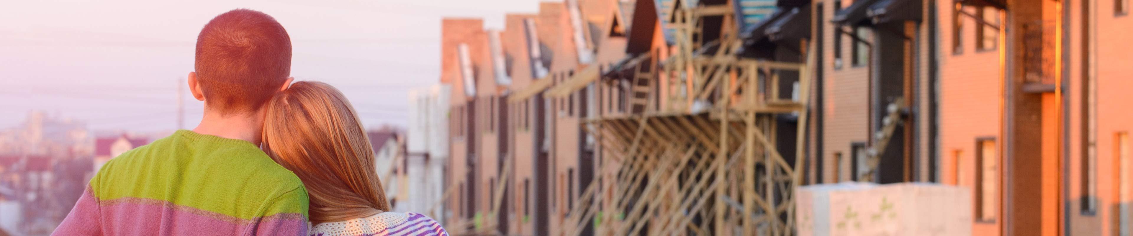 back of a couple, arm-in-arm, looking at a group of rental properties