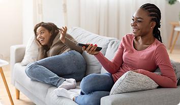 a couple of women sitting on a couch looking at a phone