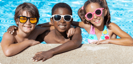 A close-up of three kids posing for a photo while standing in a swimming pool.