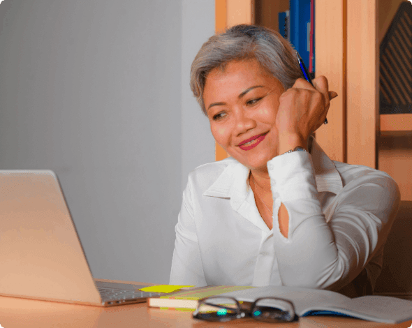 A smiling person sitting in front of their laptop.